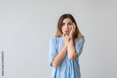 Portrait of worried young woman on light background