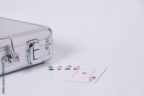 Game cards. Four cards, four aces, four symbols in background and white table and poker chips briefcase in the frame.