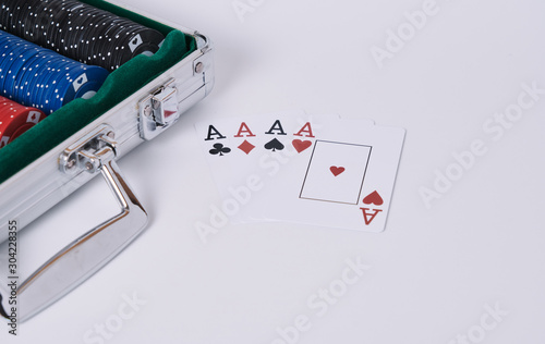Game cards. Four cards, four aces, four symbols in background and white table and poker chips briefcase in the frame.