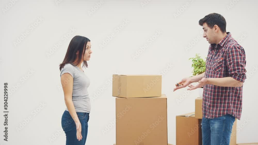 Couple is moving into new flat. They have a quarrel, because don't know where to put all those big cardboard boxes. Woman is ready to throw the box at him. Couple is moving into new flat. They have a quarrel, because don't know where to put all those big cardboard boxes. Woman is ready to throw the box at him.