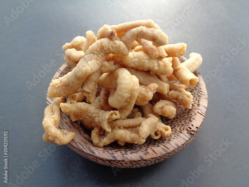 Close up view of kripik keripik usus ayam or gut chicken fried snack fritters crackers on the bowl. traditional menu from Indonesia. Clean bowels inside, covered with flour, then frying on hot oil photo