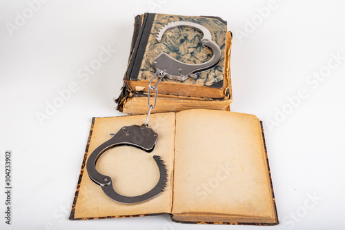 Old books and metal handcuffs. Literature and prison for bad words.