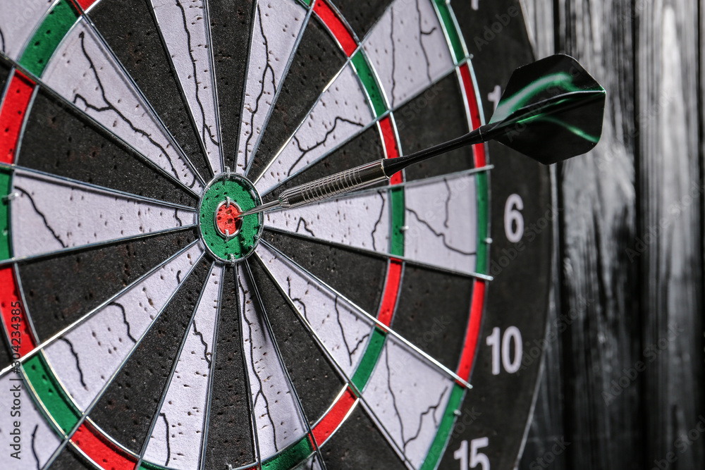 Dartboard with hit bullseye hanging on wall, closeup Dartboard with hit bullseye hanging on wall, closeup