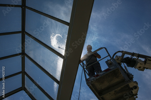 worker of Professional Facade Cleaning Services washing a galss roof
