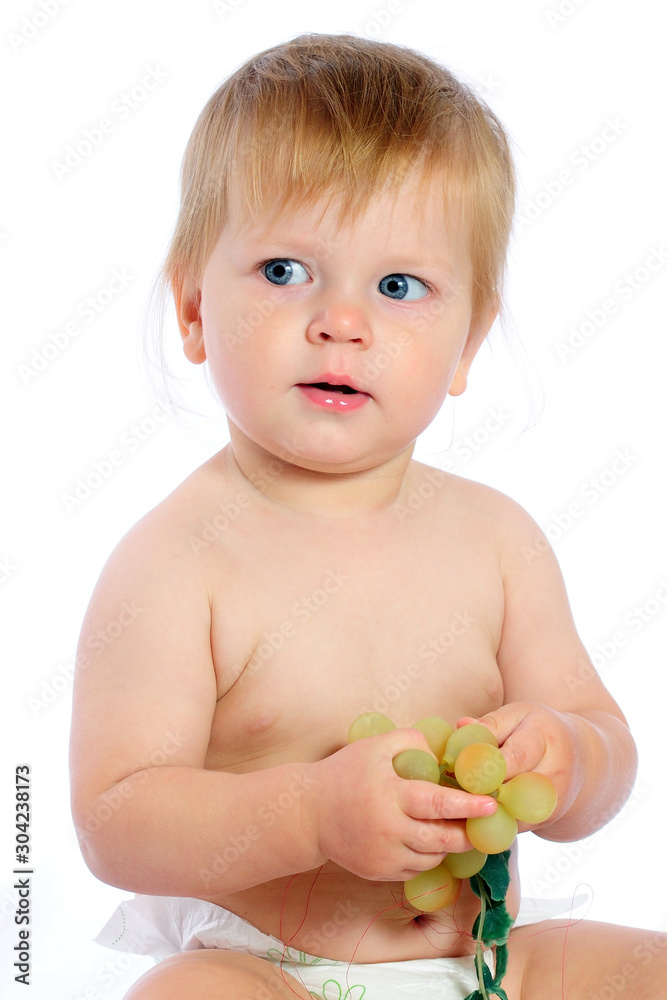 Boy sitting near wicker basket and holding grape Boy sitting near wicker basket and holding grape