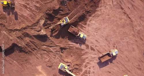 Aerial flight over earth moving machines at construction site. Construction crews prepare a site for a building . Digger, truck and bulldozer preparing ground for construction. Earthworks site.