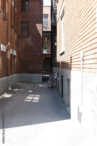 Bicycles in an alleyway lined with brick houses