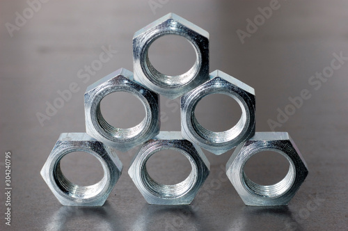 Close-up of a pyramid of five chrome metal nuts