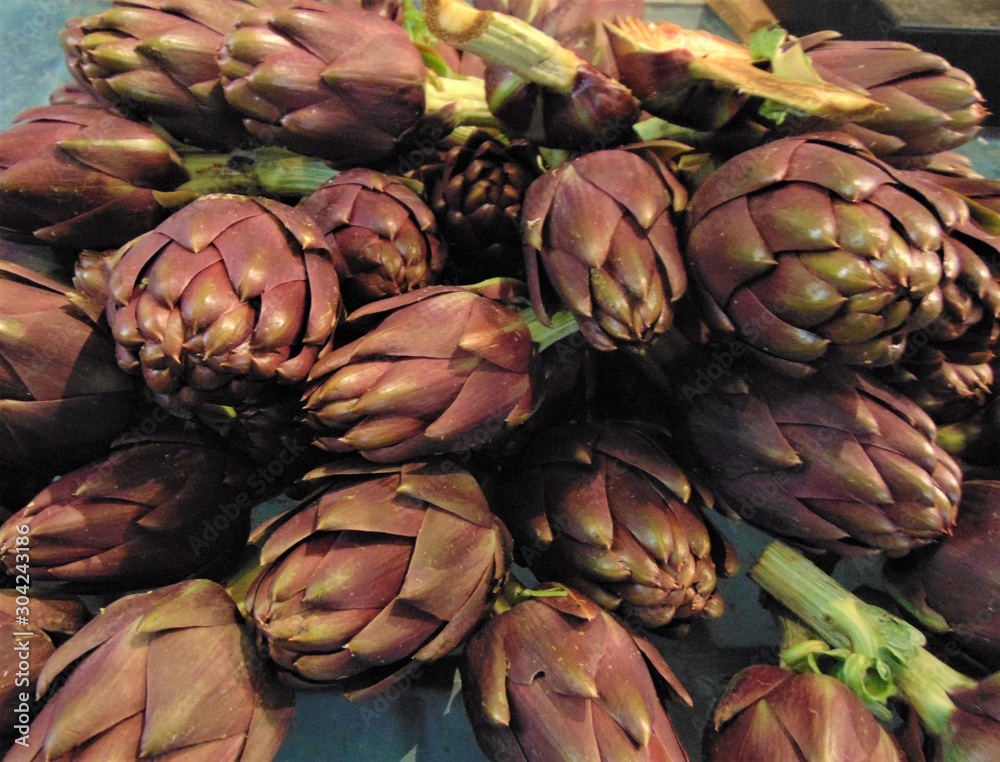 Fototapeta premium Artichokes for sale at the market. Fresh purple ripe artichokes at the vegetable market, Italia. Background, Close-up.
