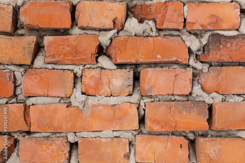 Canvas Print Old orange brick wall, uneven masonry close up.
