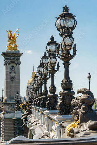 Pont Alexandre III details with the Eiffel Tower in the background, with blue sky