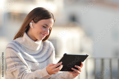 Satisfied woman e-learning using tablet in a balcony