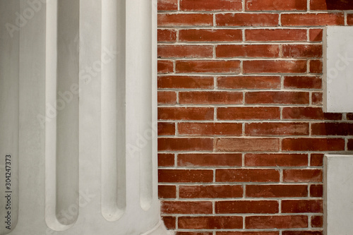 Fragment of a white column on a background of a red brick wal photo