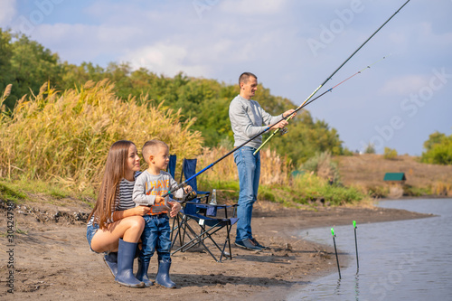 A happy family spends time together they teach their son to fish.