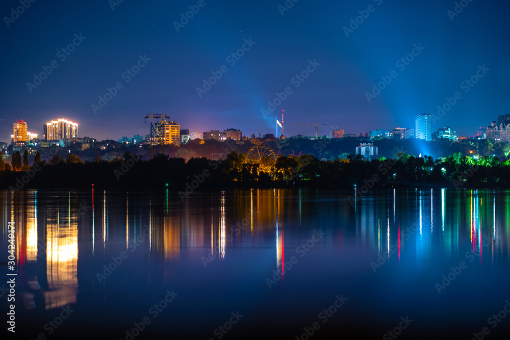 night landscape of the city promenade with many colored lights reflected in the water