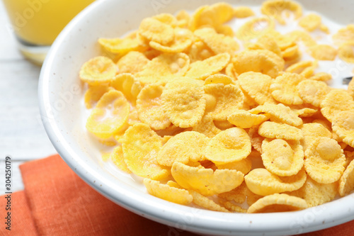 Tasty corn flakes with milk on white table, closeup