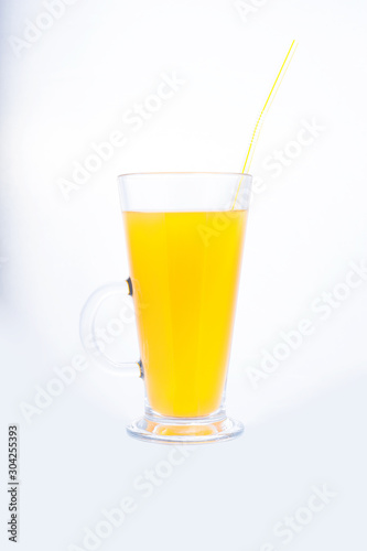 yellow aperlsin juice drink in a glass with a straw on a white background
