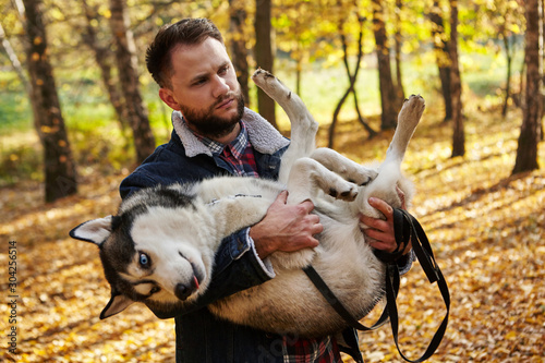 Hipster stylish guy hug his husky dog in autumn forest.Pedigree dog concept. Best friends. Unconditional love. Guy enjoy walk with husky dog. Siberian husky cool pet. Animal husbandry.