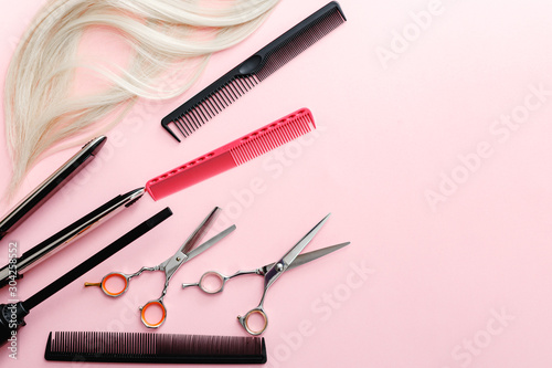 Fototapeta Naklejka Na Ścianę i Meble -  Scissors, combs, hair iron and other hairdresser's accessories and strand of blonde hair on pink background. Flat lay with space for text. Hairdresser service. Beauty salon service