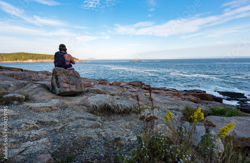 Hiker resting on rock near ocean