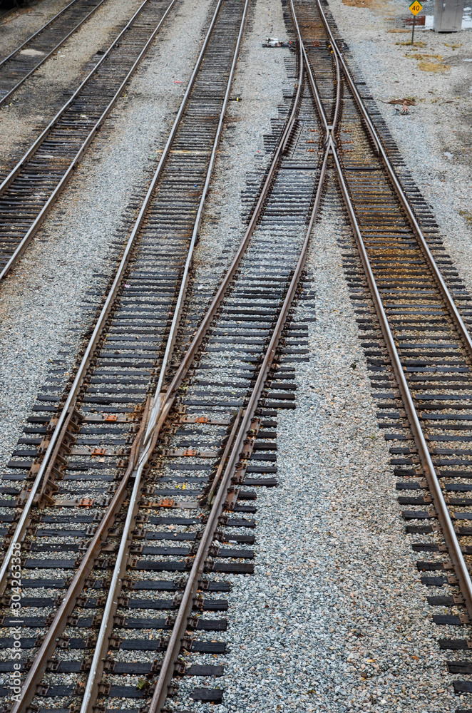 Looking down on the train tracks in a railroad yard. May rows of train tracks and switches are visible.