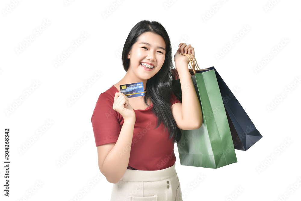 Beautiful Asian woman wearing braces are holding up a credit card and shopping bag happily. Beautiful Asian woman wearing braces are holding up a credit card and shopping bag happily.