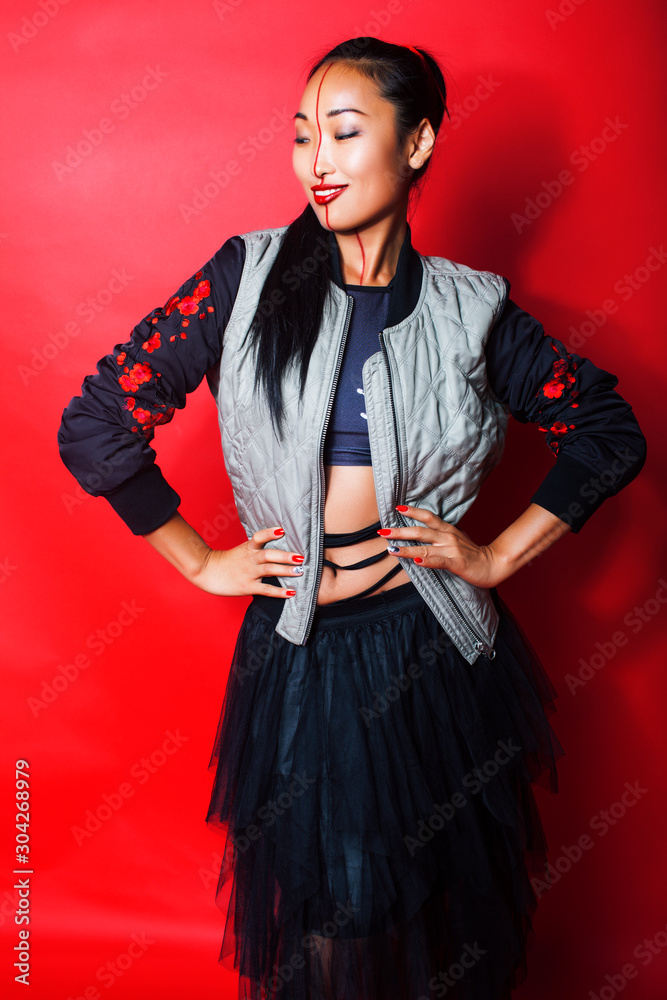 Fototapeta premium young pretty asian girl posing cheerful on red background, fashion makeup and clothers