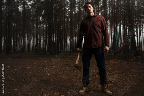 Strong lumberjack with the ax in the forest.Stylish lumberman getting ready for work. Lifestyle.