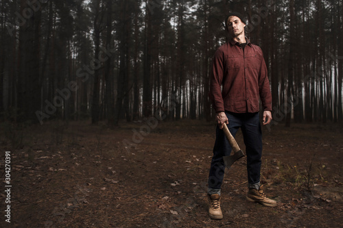 Strong lumberjack with the ax in the forest.Stylish lumberman getting ready for work. Lifestyle.