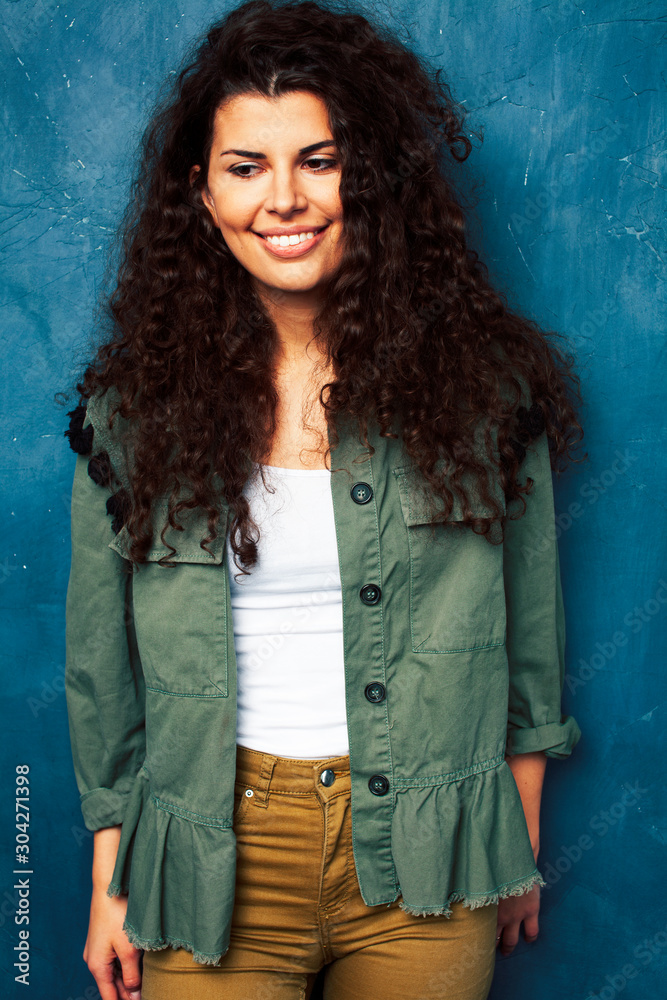 young pretty brunette girl with curly hair posing cheerful happy smiling on blue background, lifestyle people concept young pretty brunette girl with curly hair posing cheerful happy smiling on blue background, lifestyle people concept