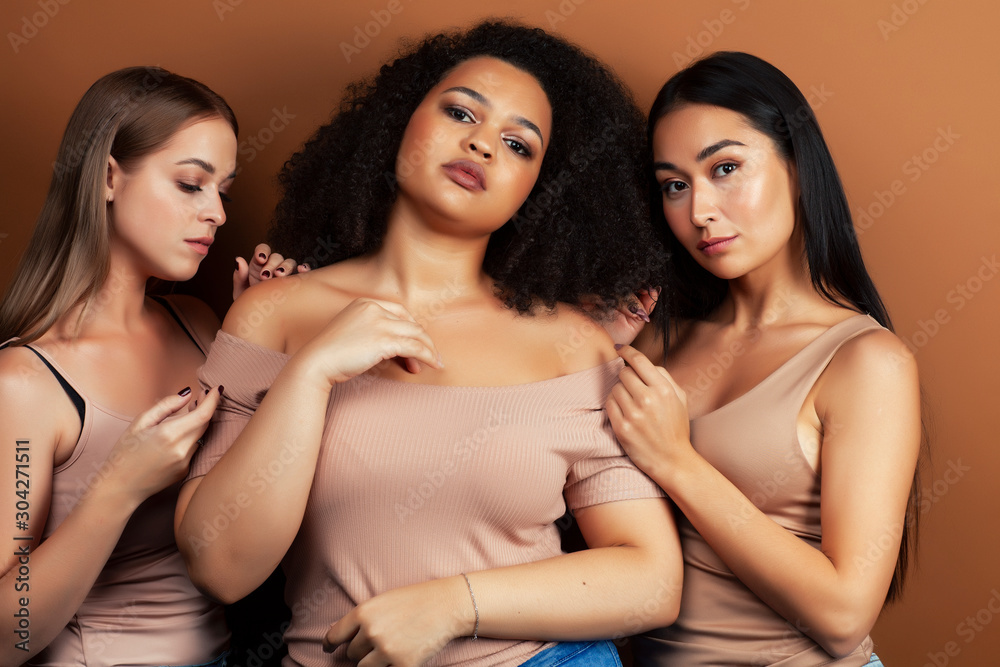 young pretty asian, caucasian, afro woman posing cheerful together on brown background, lifestyle diverse nationality people concept young pretty asian, caucasian, afro woman posing cheerful together on brown background, lifestyle diverse nationality people concept