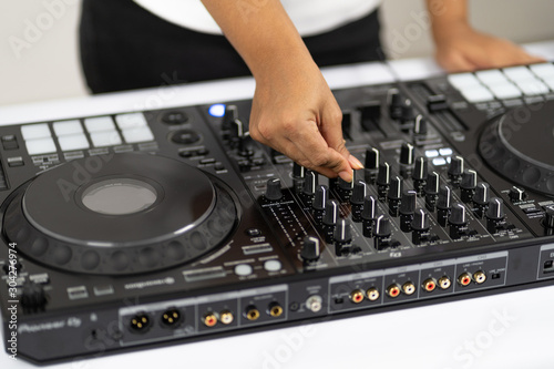 Hands of DJ mixing tracks on professional sound mixer.Fashionable rings on fingers of girl disc jockey playing music.Closeup knobs and regulators in focus.Girl dj play music tracks at house party