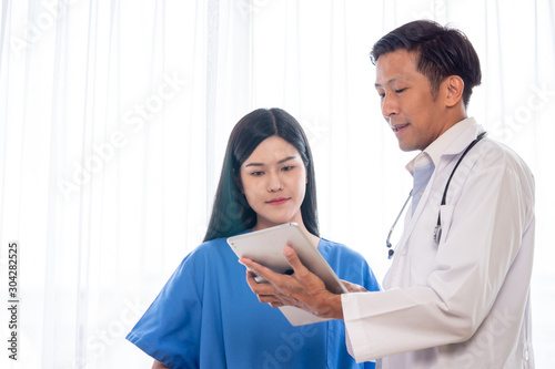 Asian doctor explaining works from tablet to medical assistants.