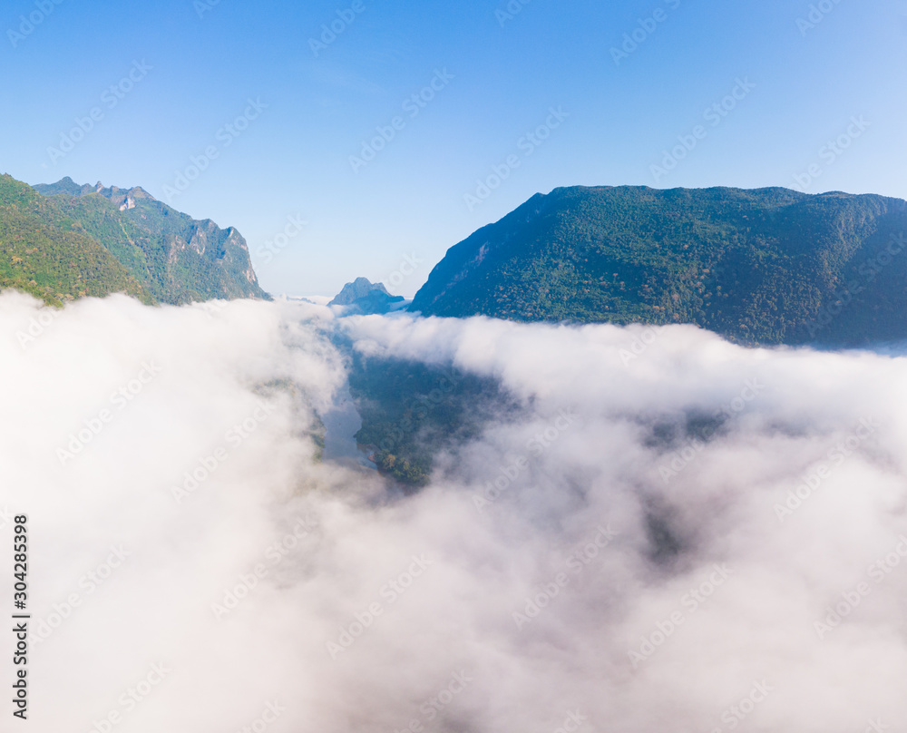 Aerial panoramic Nam Ou River drone flying over morning fog mist and clouds, Nong Khiaw Muang Ngoi Laos, dramatic landscape scenic pinnacle cliff, famous travel destination in South East Asia