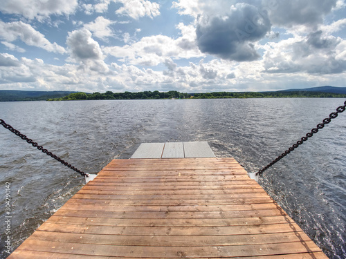 View over ferry metal boat against the wavy lake water