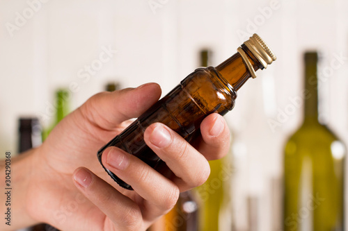 young woman holding an empty glass liquor bottle. empty liquor bottles as a background