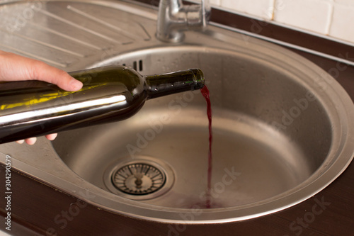 young woman dumping wine from a bottle down the drain