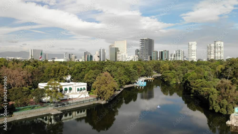 Aerial over Chapultepec Lake with drone slowly descending with views of Polanco and a blue sky as background Aerial over Chapultepec Lake with drone slowly descending with views of Polanco and a blue sky as background