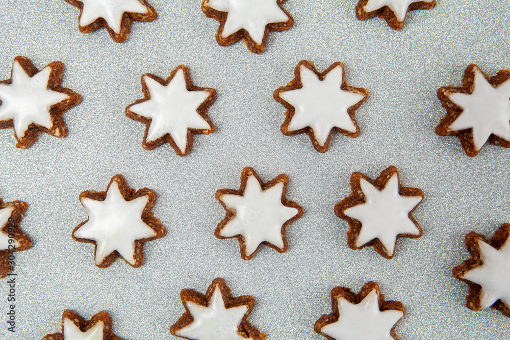 Almond stars with icing biscuits pattern on silver glitter background Almond stars with icing biscuits pattern on silver glitter background