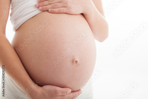 Pregnant belly close up on white background with negative copy space