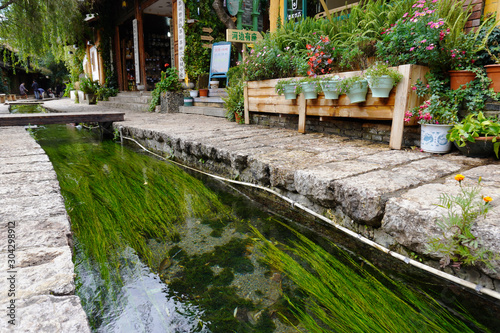 Lijiang is famous for its ancient architecture and orderly system of waterways. The clean canal flowing around the old town with water grass growing inside.
