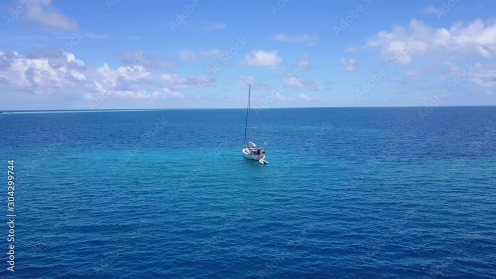 A White Tourist Yacht Sailing Into The Sea By The Island Of Tahiti With A Raft Tied Behind It - Aerial Shot A White Tourist Yacht Sailing Into The Sea By The Island Of Tahiti With A Raft Tied Behind It - Aerial Shot