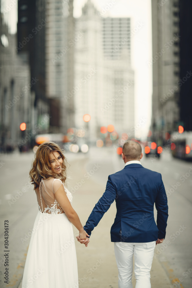 Beautiful bride in a long white dress. Handsome fiance in a blue suit. Couple in a big city