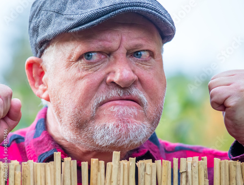 Close-up of a senior man with flat cap. He looks grim and aggressive. Concept: neighborhood and quarrel photo