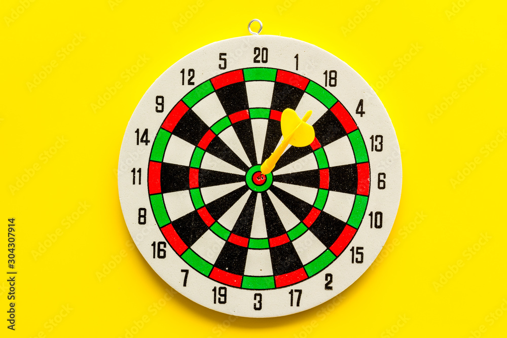 Accuracy of precision concept. Dartboard and arrows on yellow background top view copy space Accuracy of precision concept. Dartboard and arrows on yellow background top view copy space