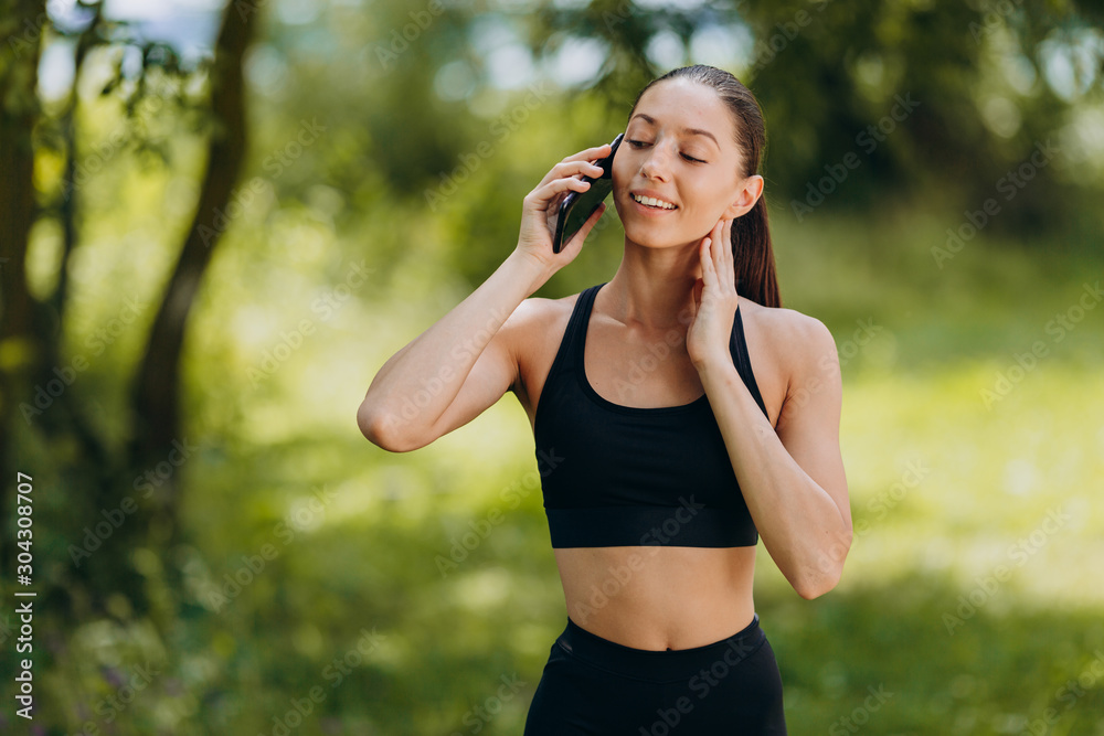 Pretty woman standing in the park and talking a smartphone outdoor. - Image Pretty woman standing in the park and talking a smartphone outdoor. - Image