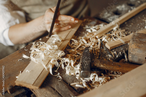 Man working with a wood. Carpenter in a white shirt