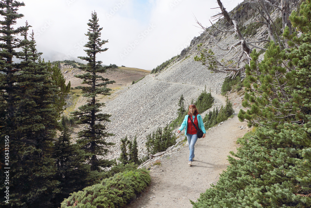 Happy woman walking along a mountain trail near Mount Rainier, Washington State, USA