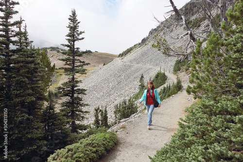 Happy woman walking along a mountain trail near Mount Rainier, Washington State, USA