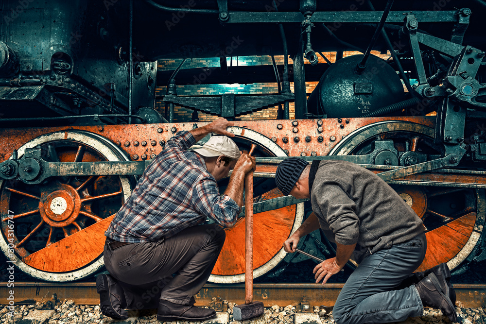 Two mechanics repair an old steam locomotive in a depot
